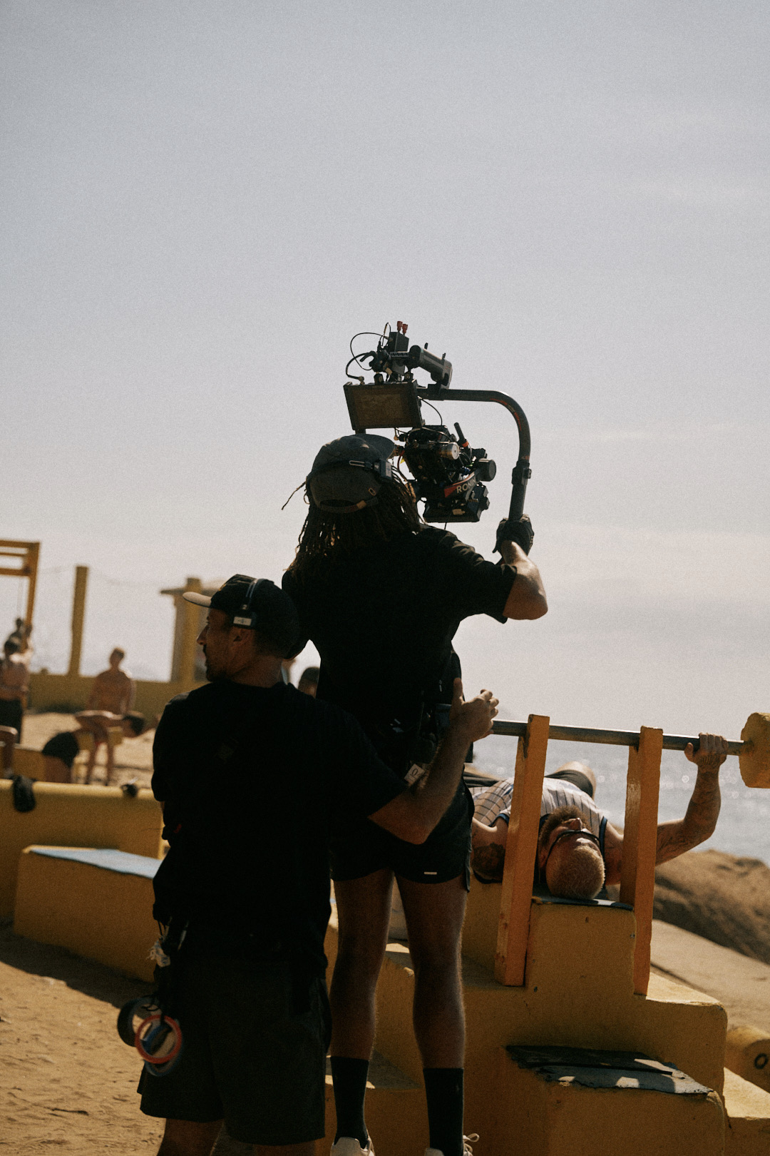 Camera crew filming a workout scene by the sea